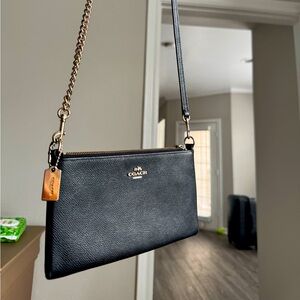 Crossbody small black leather coach bag. Gold chain and details.
